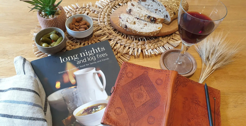 A tea towel, cookbook and tapas arrangement with a glass of wine on a kitchen table