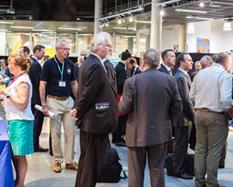 Large group of people networking in a hall with stalls around the edge