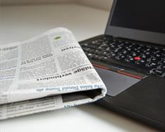 Newspaper next to laptop on a table